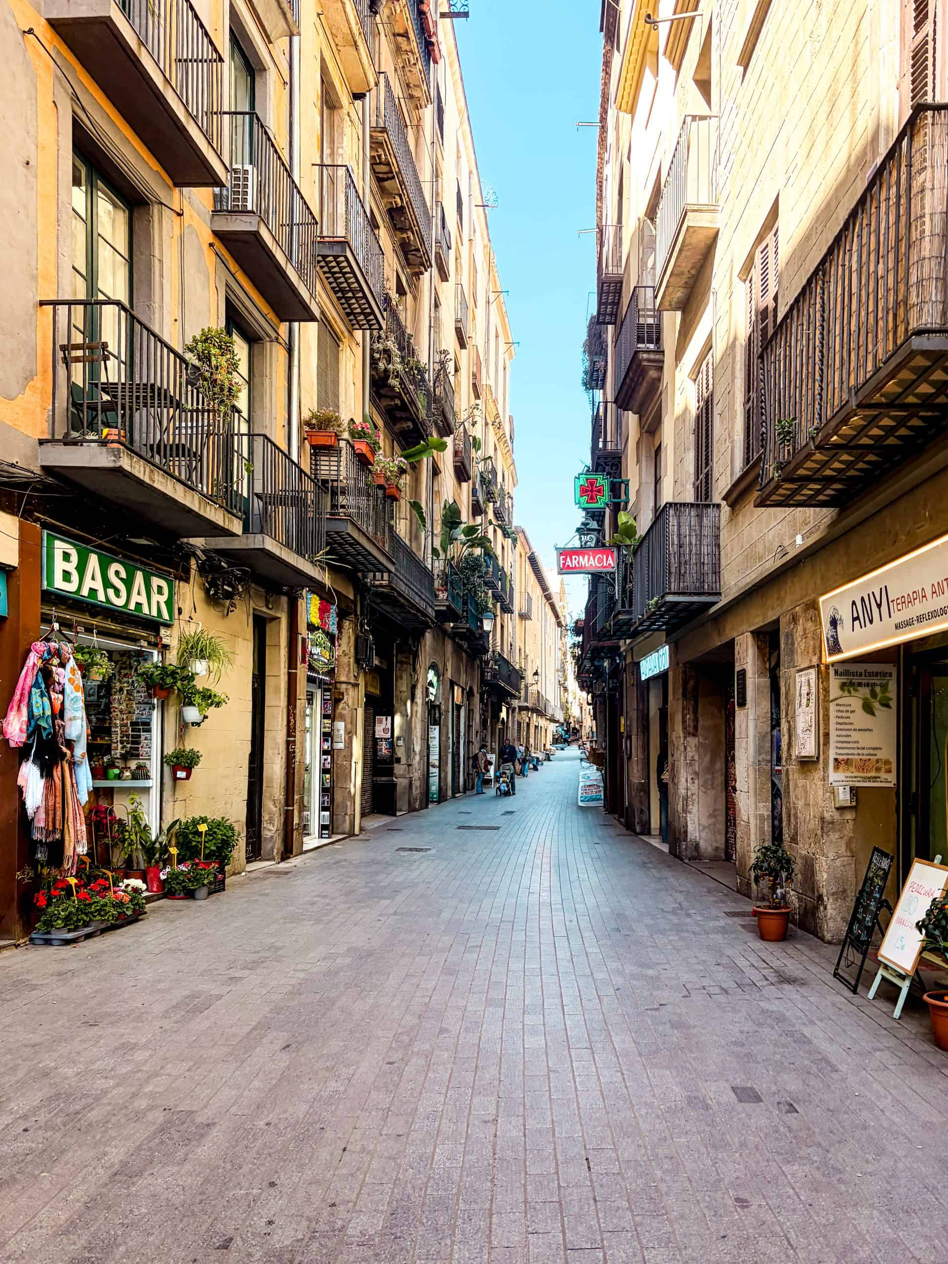Cobblestones line a narrow alley flanked by tall stone walls in the Gothic Quarter