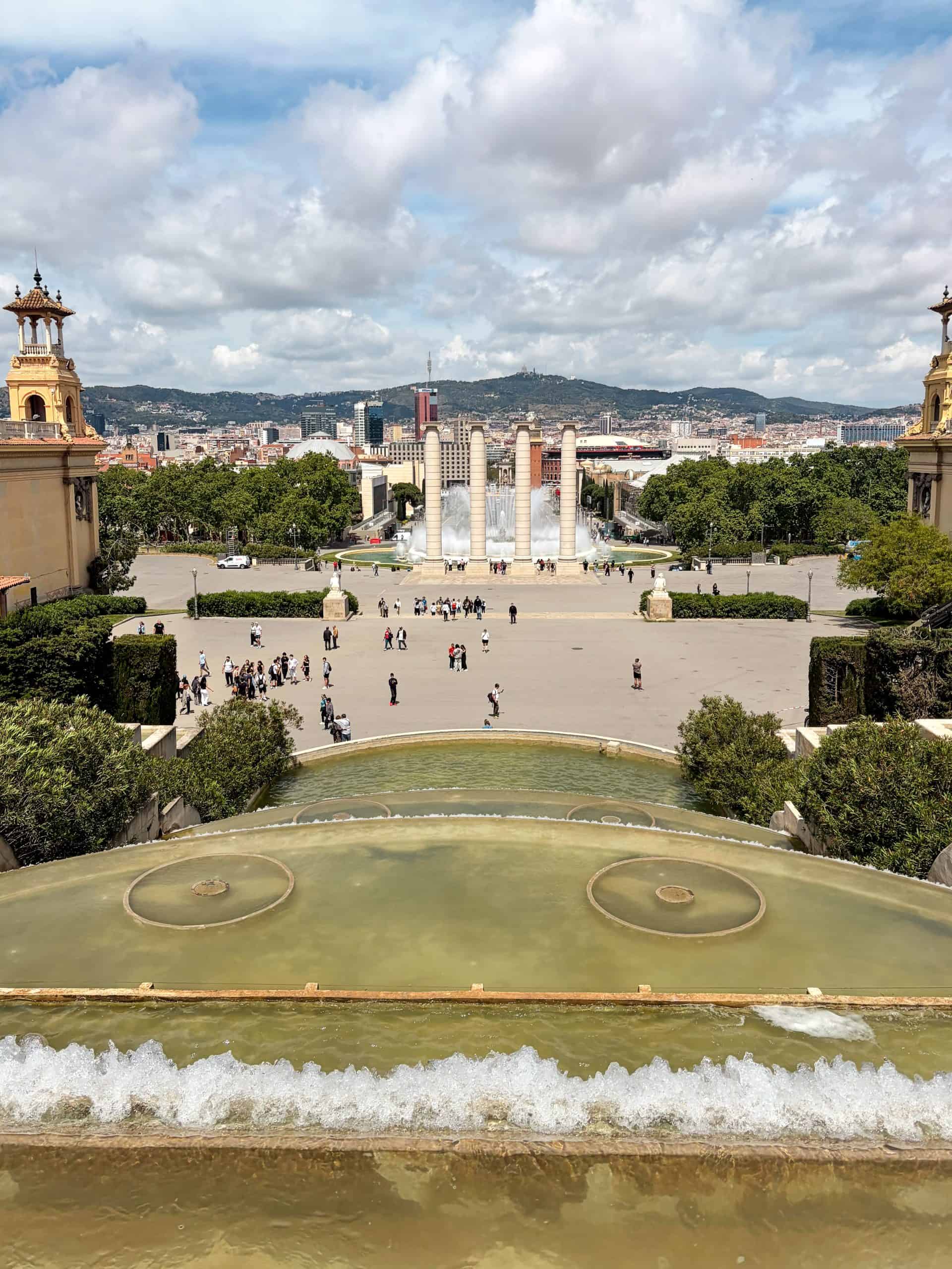 Cascading fountains below the MNAC lead toward the four columns and Barcelona skyline
